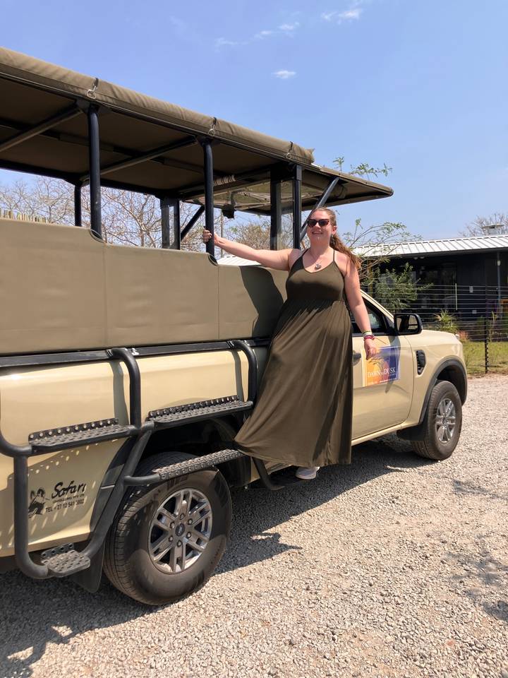 Femme posant sur un véhicule de safari.