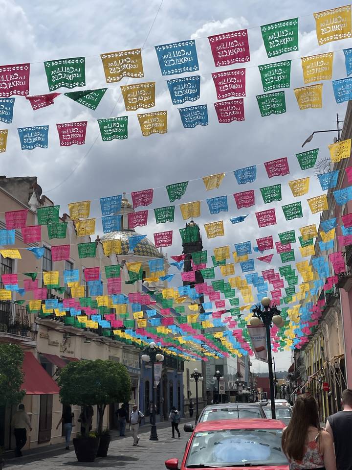 Rue décorée de drapeaux colorés et de gens qui marchent.