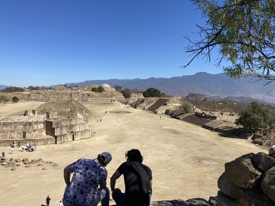 Deux personnes regardant des ruines antiques avec des montagnes en arrière-plan.