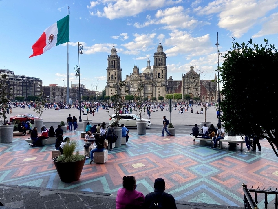 Plan large d'une place publique avec des gens et une grande cathédrale.
