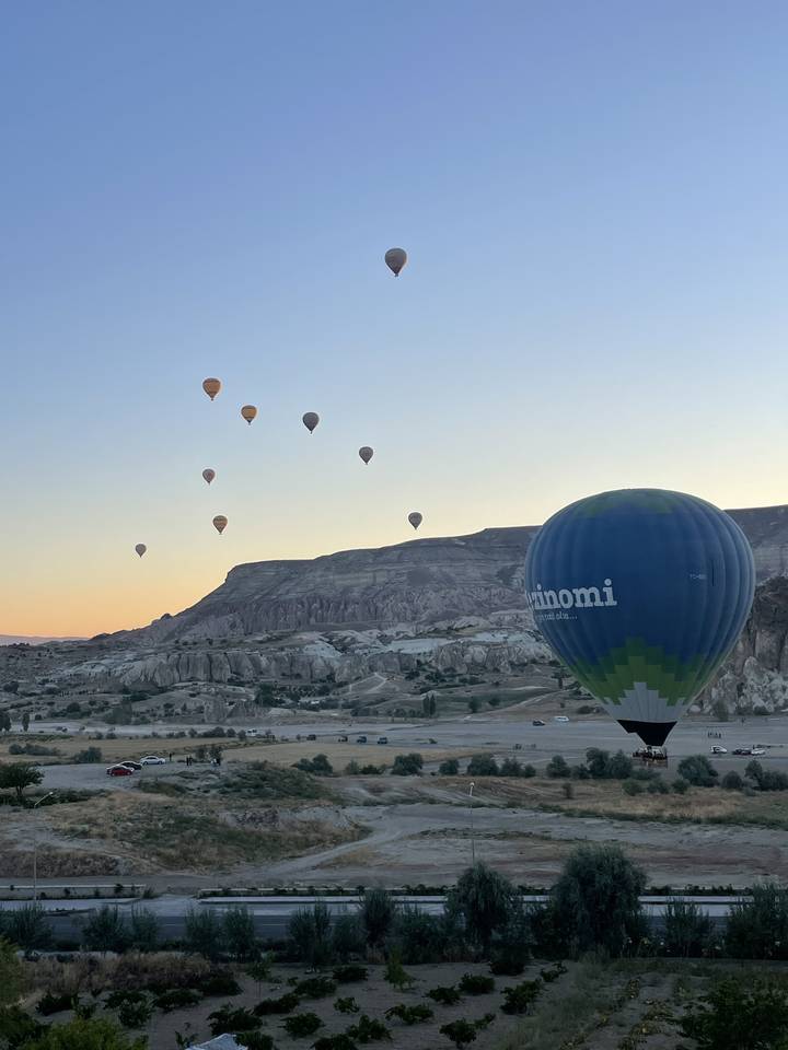 Montgolfières survolant un paysage pittoresque au lever du soleil.