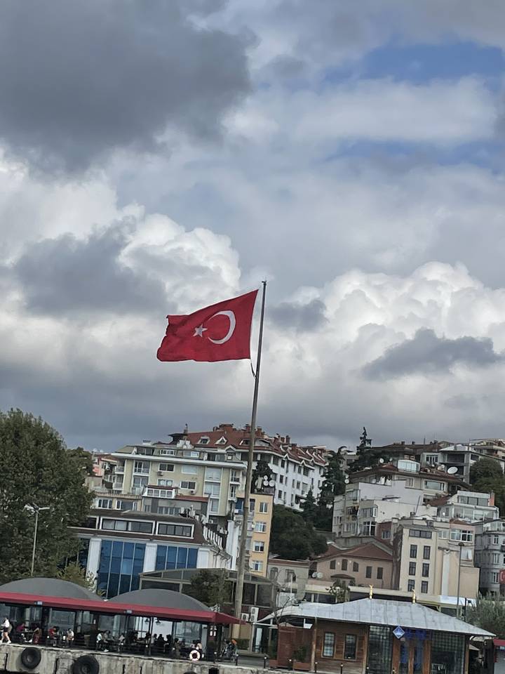 Drapeau turc flottant dans le vent avec des bâtiments en arrière-plan.