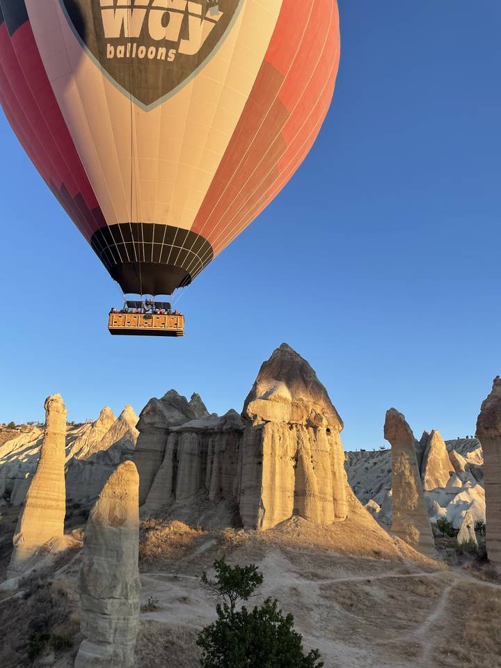 Montgolfière volant au-dessus de formations rocheuses.