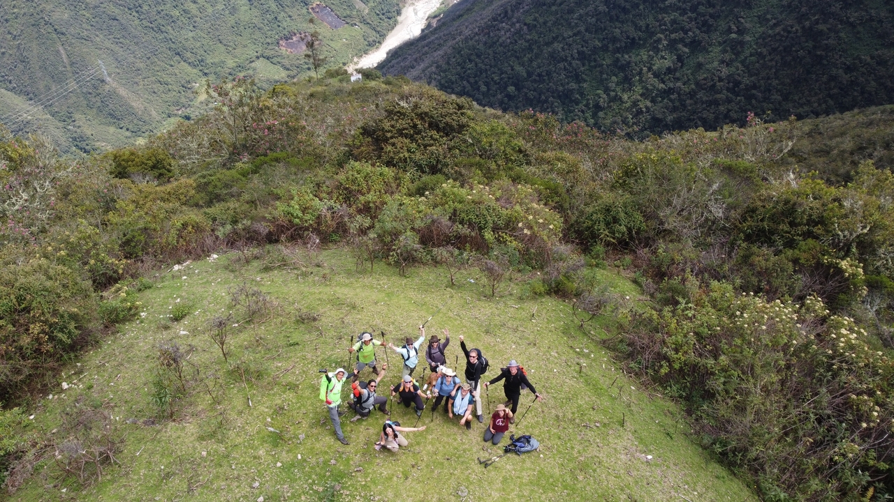 A group of people posing on a mountain with a scenic view.