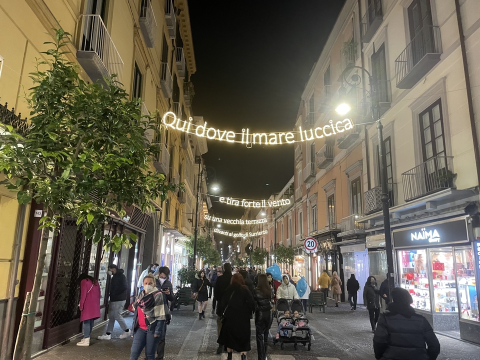 Une rue décorée avec du texte italien illuminé la nuit.