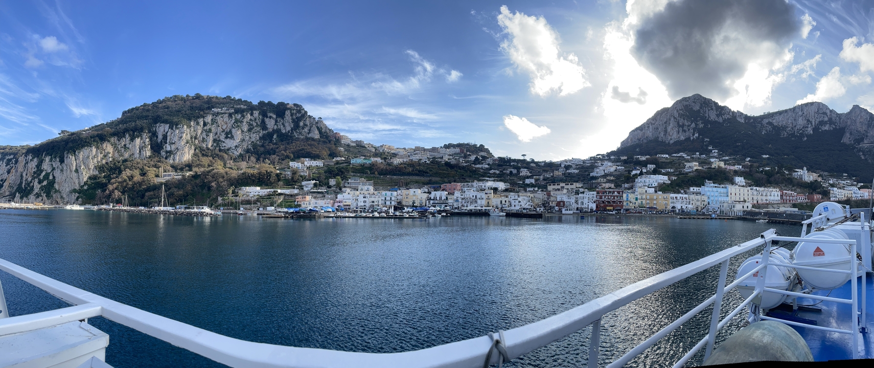 Vue panoramique d'une ville côtière avec des montagnes et un port.
