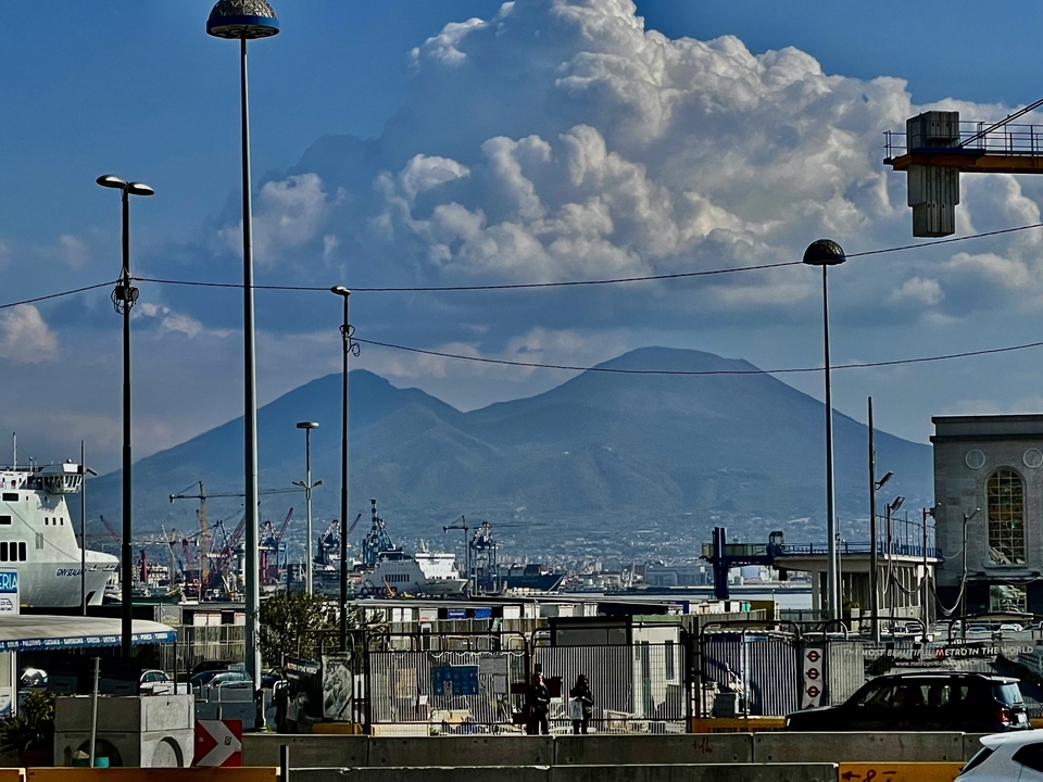 Un port avec des navires à quai et un volcan au loin.