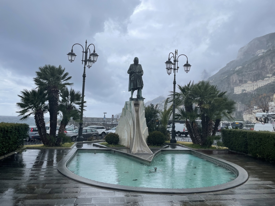 Statue dans un cadre de jardin avec des palmiers et des montagnes en arrière-plan.
