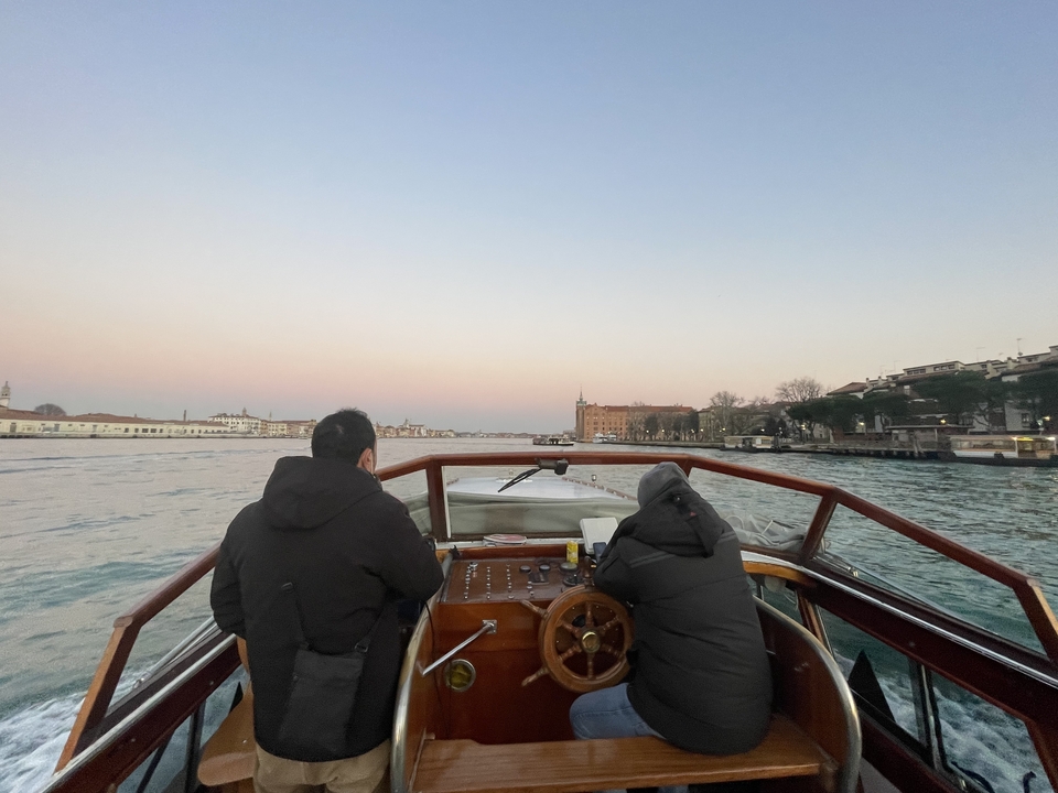 Deux personnes sur un bateau au coucher du soleil avec vue sur la ville.