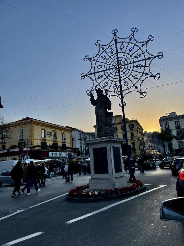 Une place urbaine animée avec une statue et des décorations illuminées.