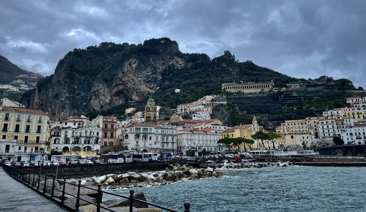 Une ville côtière aux bâtiments colorés sur fond de montagnes.
