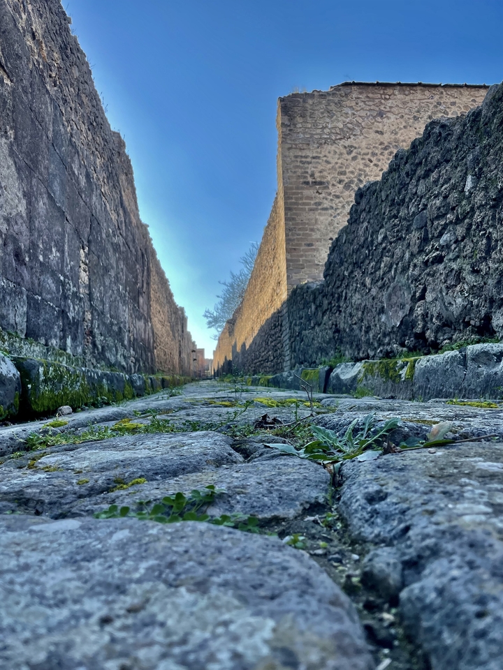 Une ancienne rue pavée bordée de hauts murs.