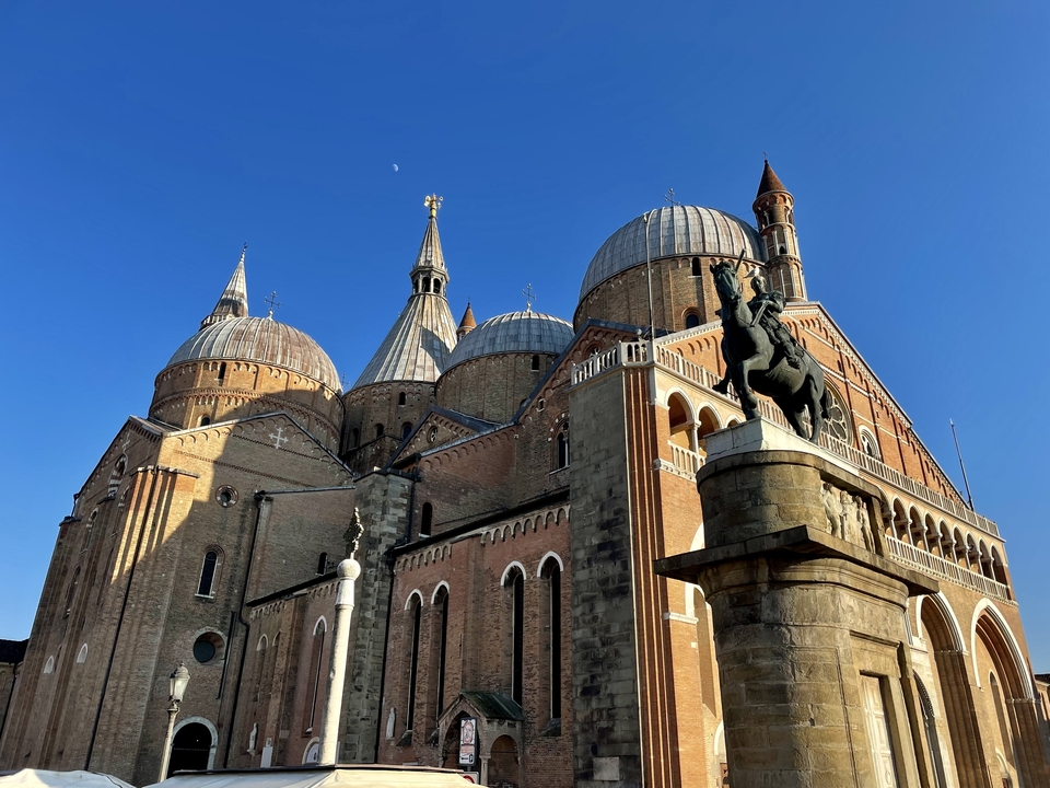 Une église avec plusieurs dômes et une statue devant.