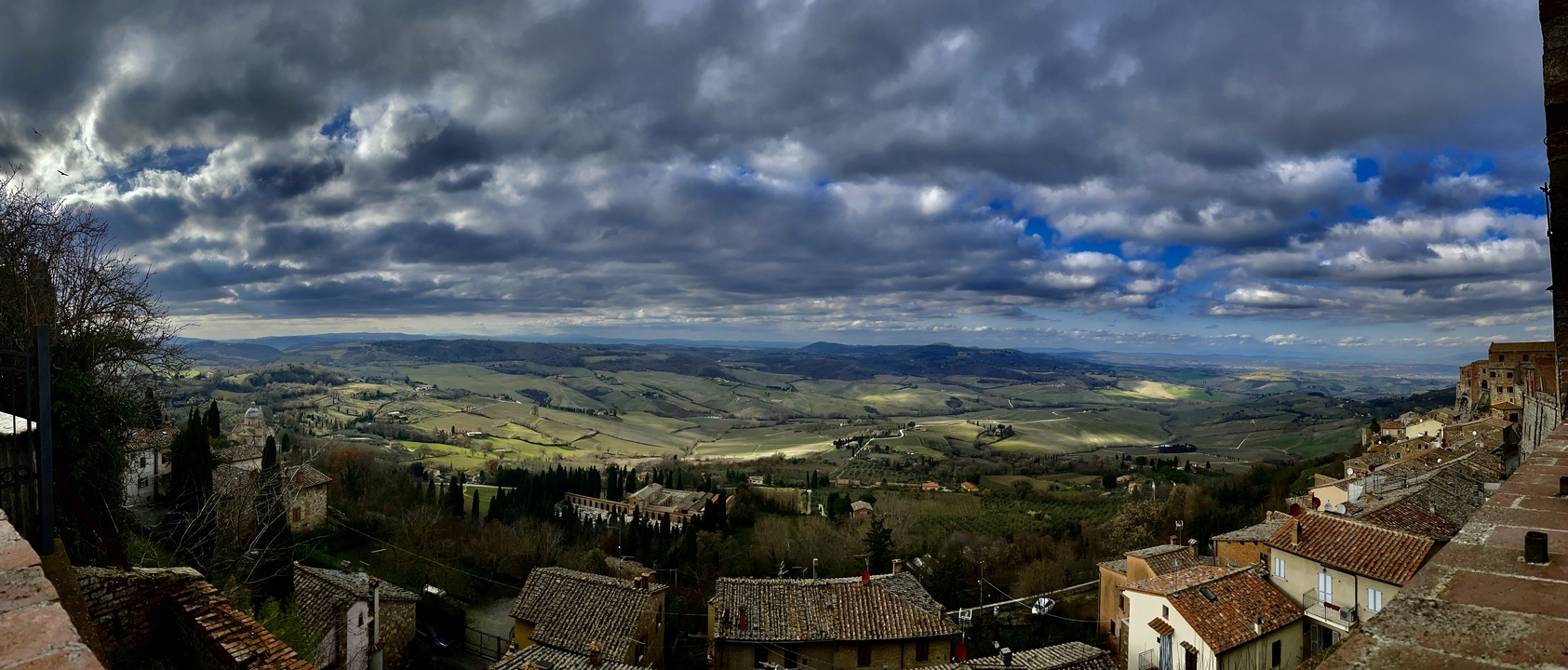 Une vue large de la campagne toscane avec des nuages épars.