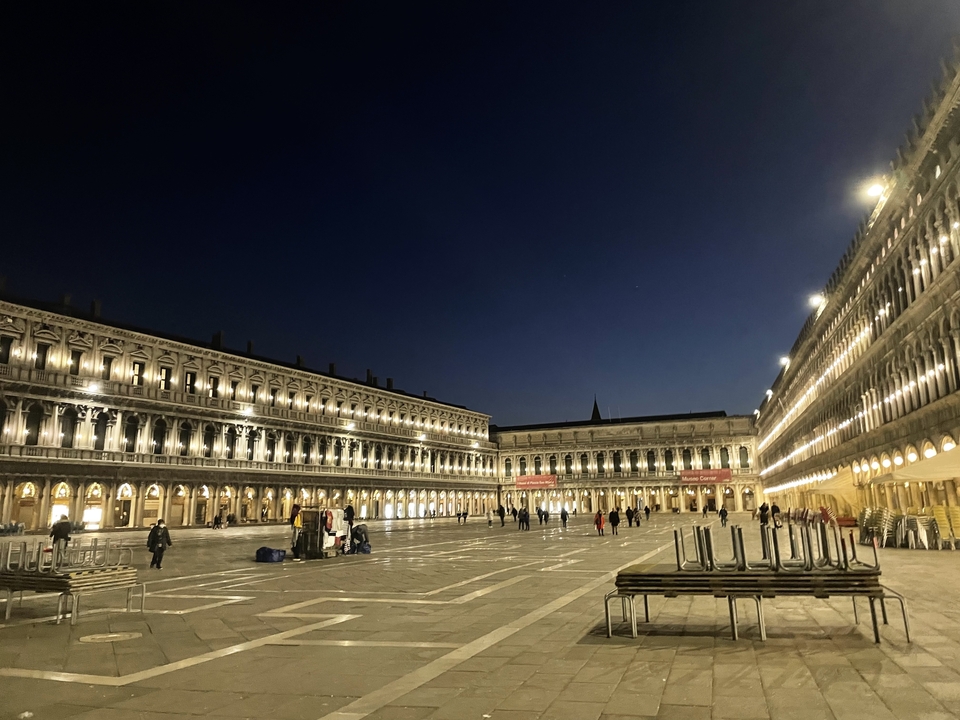 Une large place avec des bâtiments illuminés la nuit.