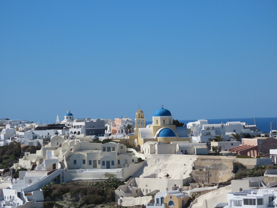 Bâtiments blancs avec des dômes bleus et la mer en arrière-plan.