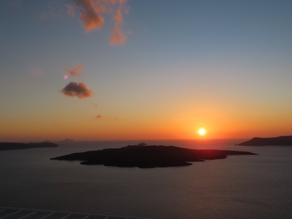 Vue du coucher de soleil sur la mer avec des îles au loin.