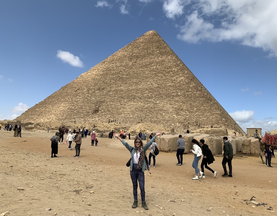 Des gens devant une grande pyramide sous un ciel dégagé.