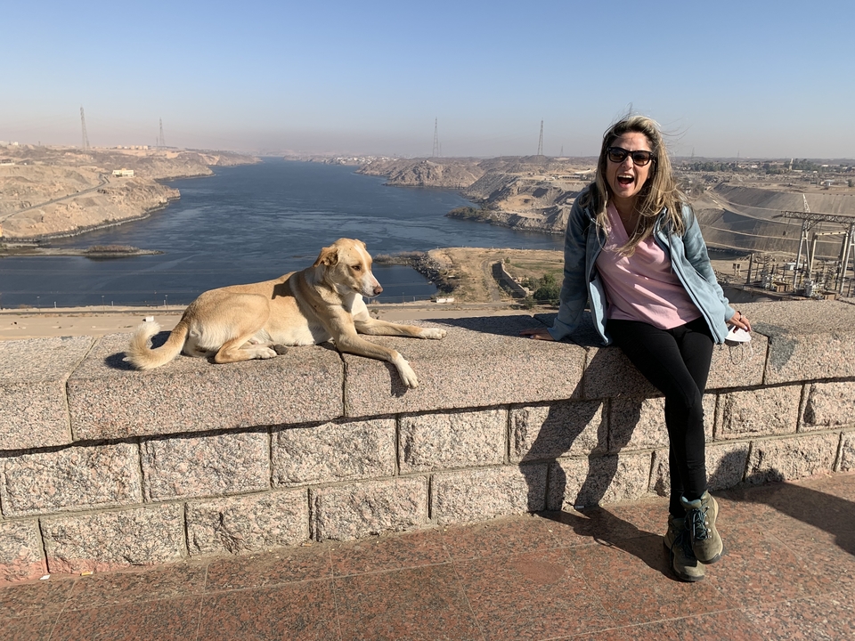 Personne posant avec un chien surplombant une rivière avec un sourire.