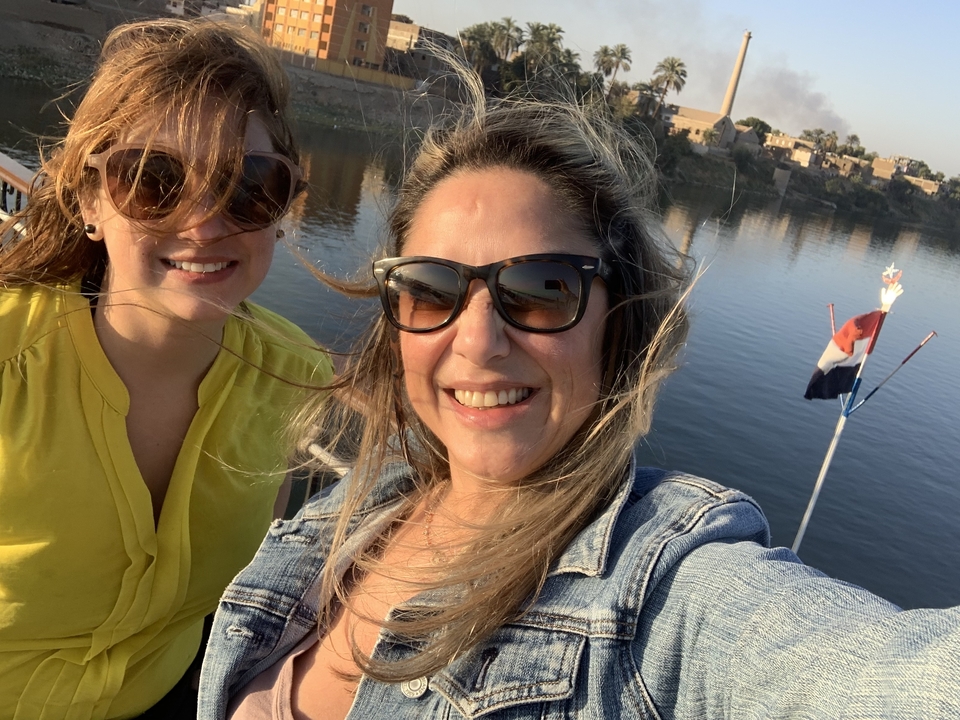 Deux femmes sur un bateau avec une rivière et des bâtiments en arrière-plan.