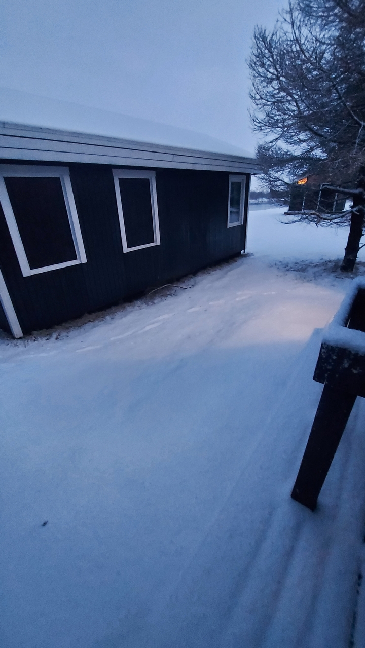 Sol enneigé avec un bâtiment partiellement visible.