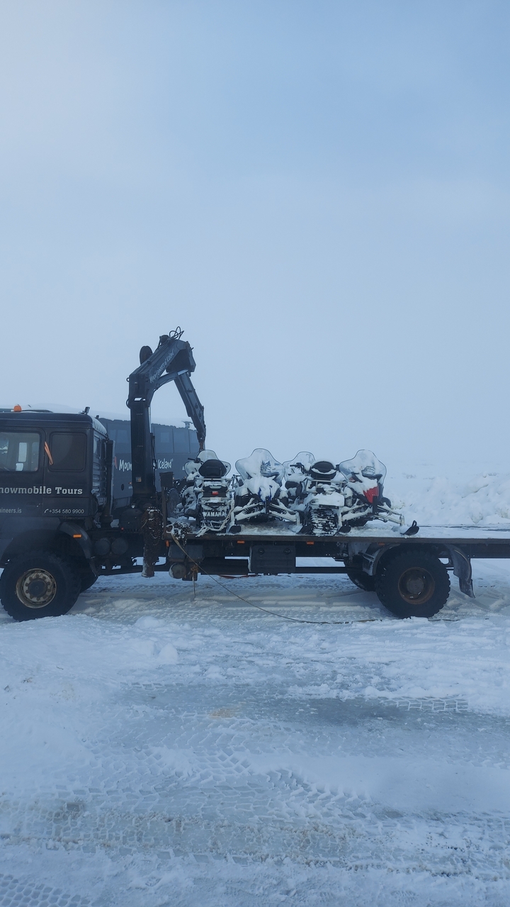 Camion transportant des motoneiges dans un paysage enneigé.