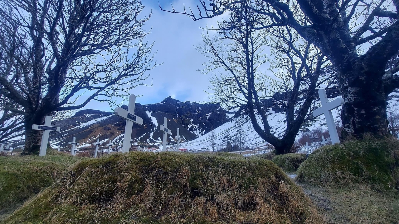 Ancien cimetière avec toile de fond de montagnes enneigées.
