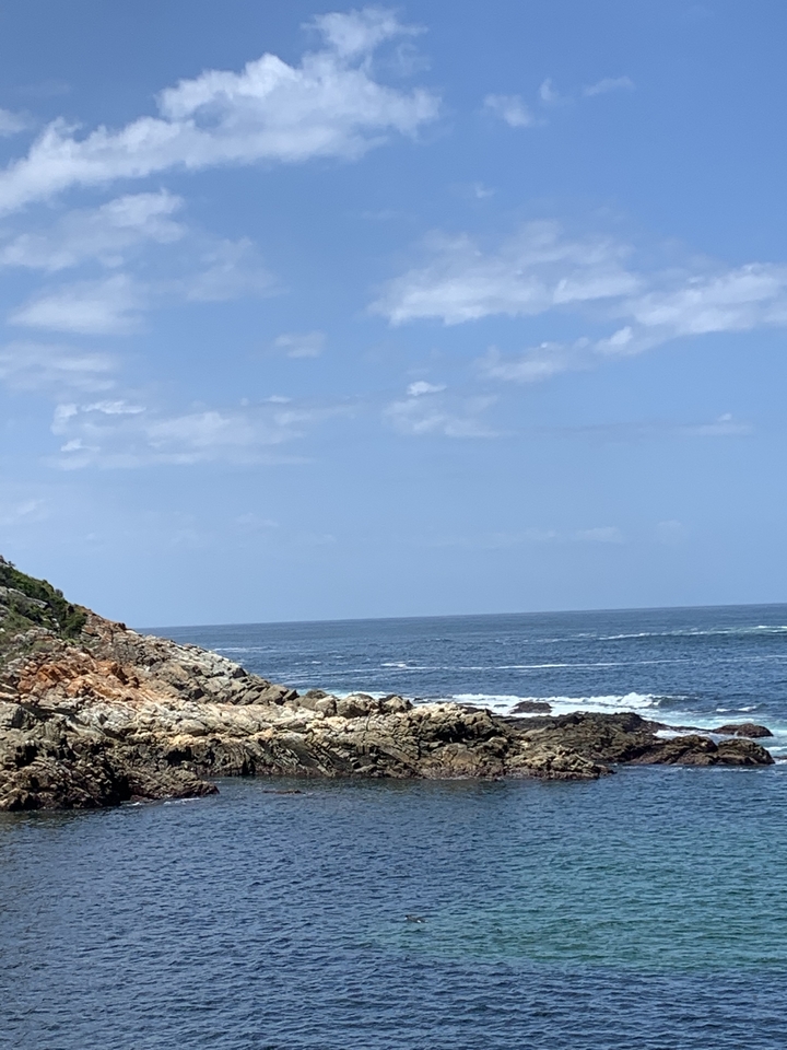 Côte rocheuse avec des vagues sous un ciel partiellement nuageux.