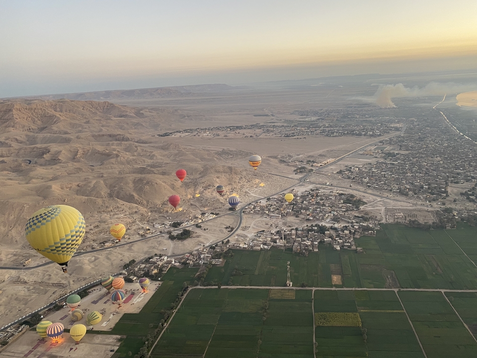 Montgolfières volant au-dessus d'un paysage désertique à l'aube.