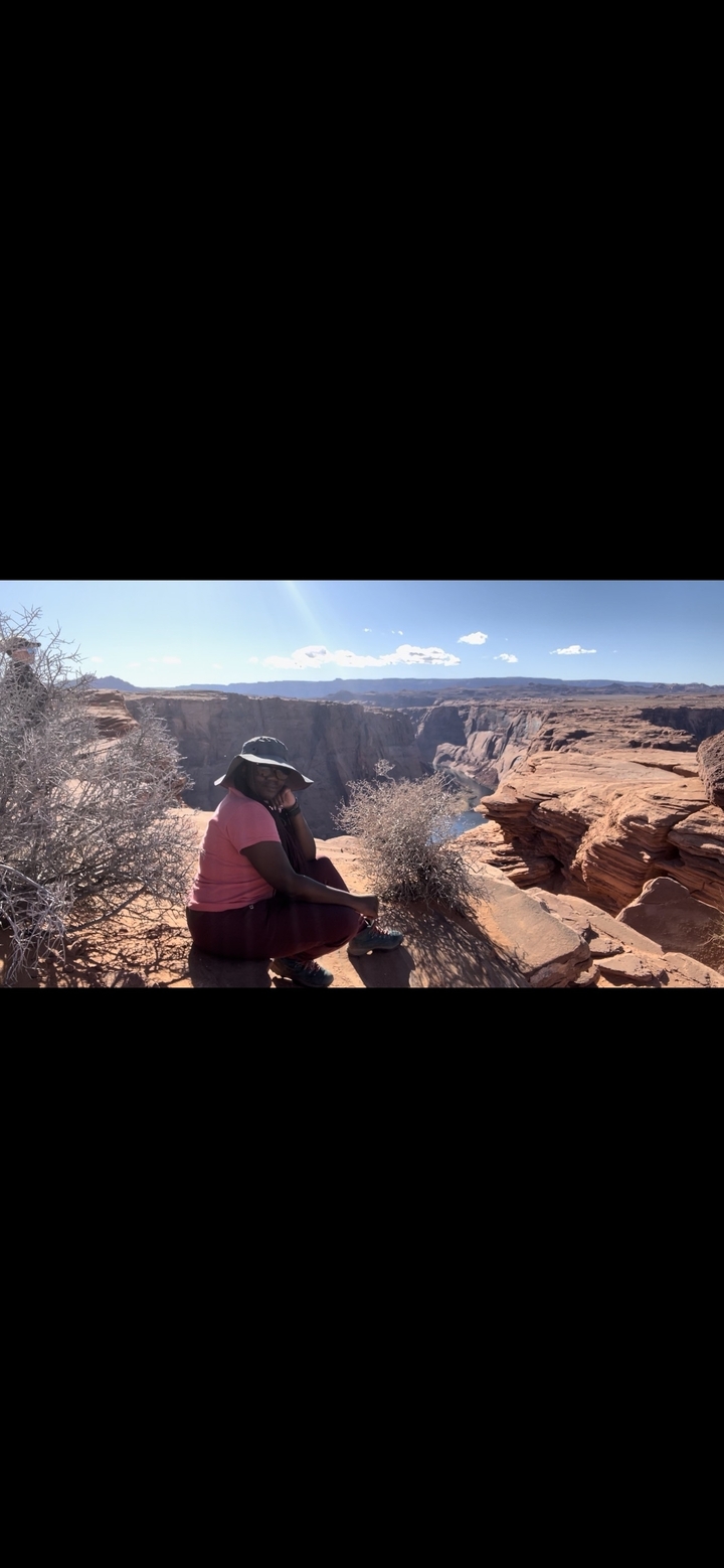 Une personne assise au bord d'un canyon.