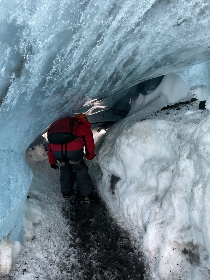 Une personne explorant une grotte de glace.