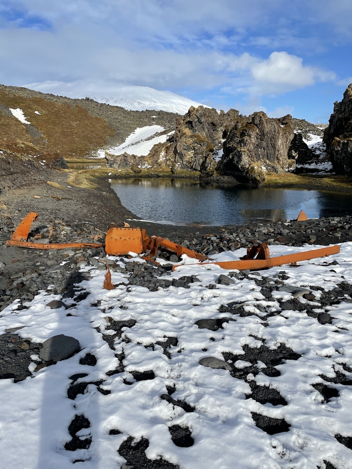 Épave rouillée près d'un petit plan d'eau.