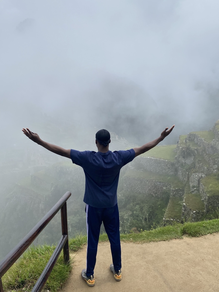 Personne les bras étendus contemplant le Machu Picchu brumeux.