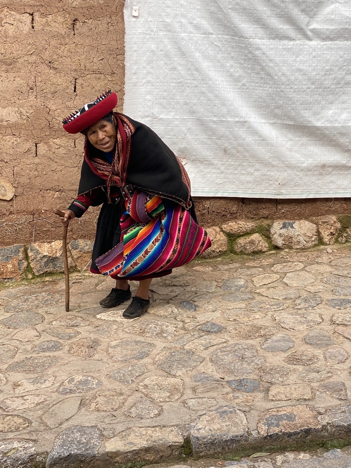 Femme andine en tenue traditionnelle marchant sur un chemin pavé.
