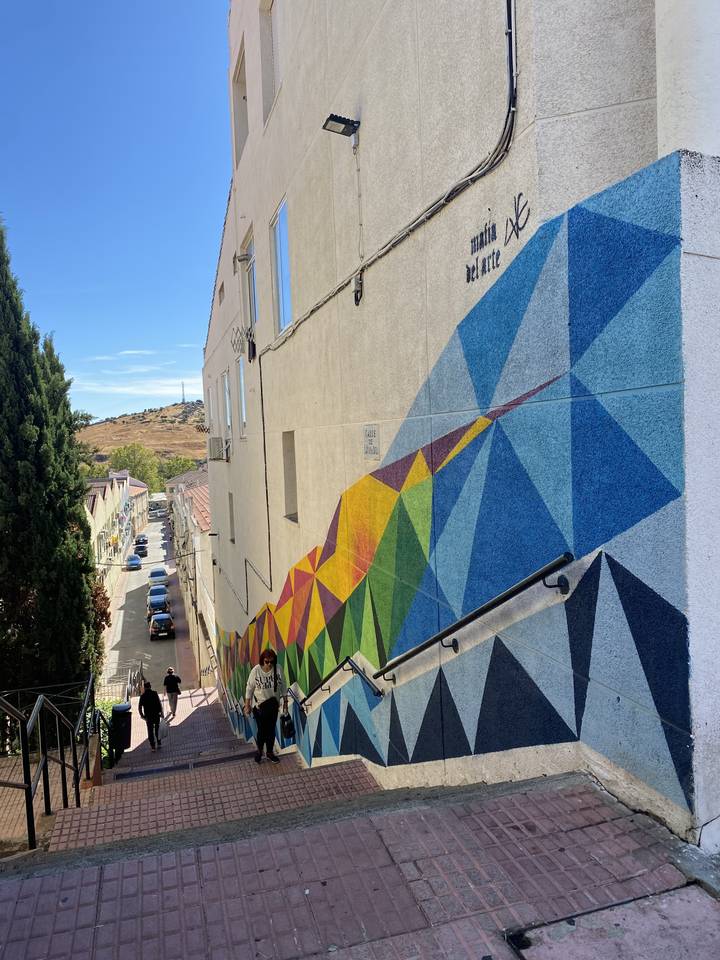 Rue avec une fresque colorée et des gens qui marchent le long d'un passage piéton.