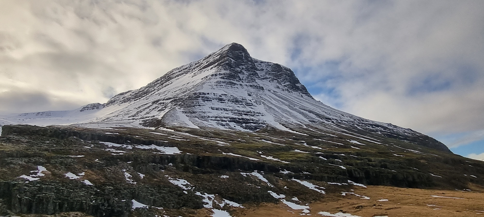 Une montagne enneigée sous un ciel nuageux.
