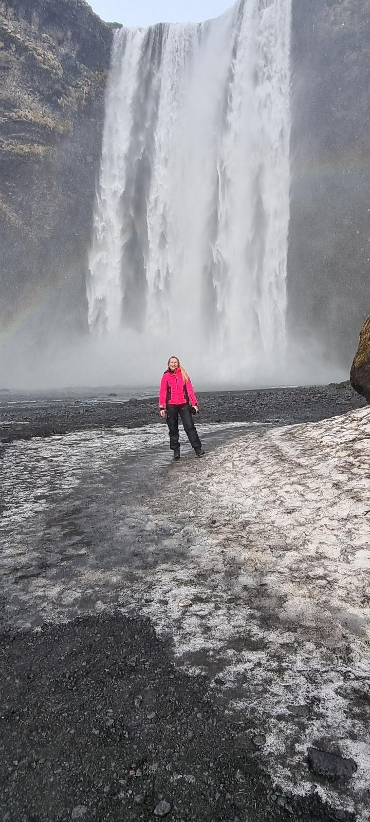 Une personne debout devant une cascade.