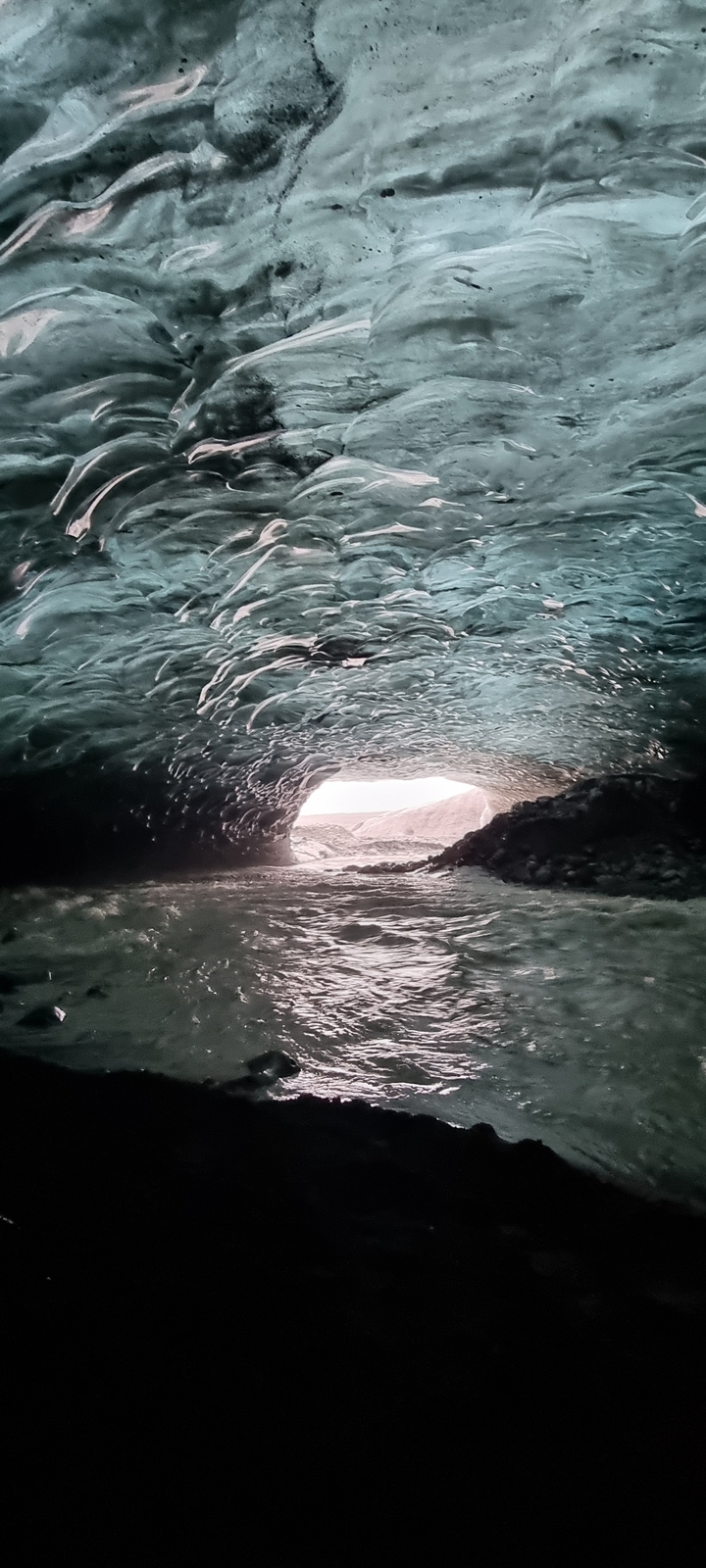 Une vue à l'intérieur d'une grotte de glace, avec de l'eau qui s'écoule à travers.