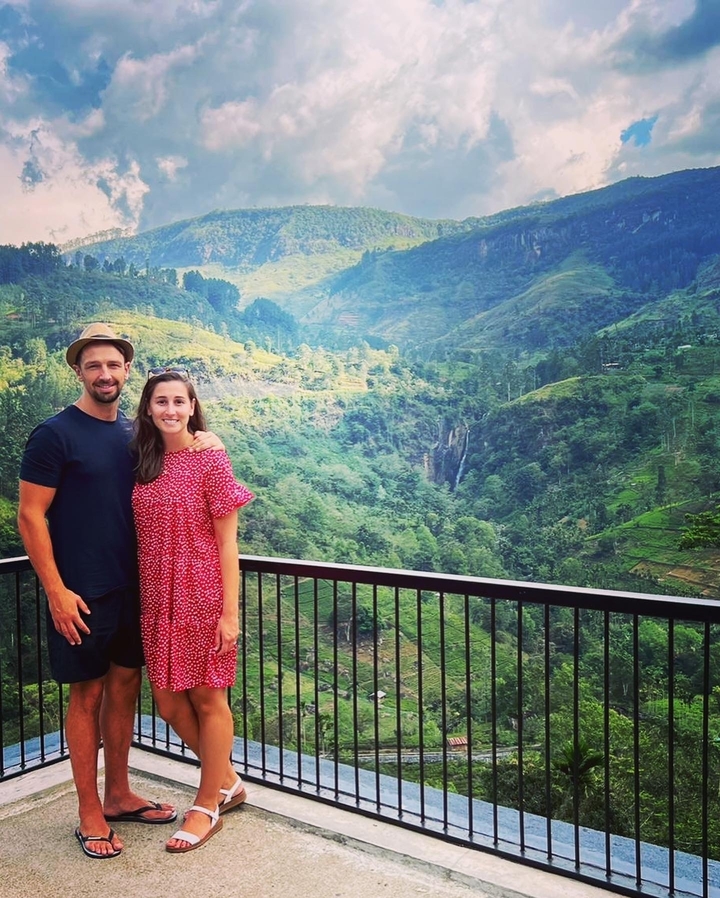 Couple debout sur un balcon surplombant des montagnes luxuriantes.