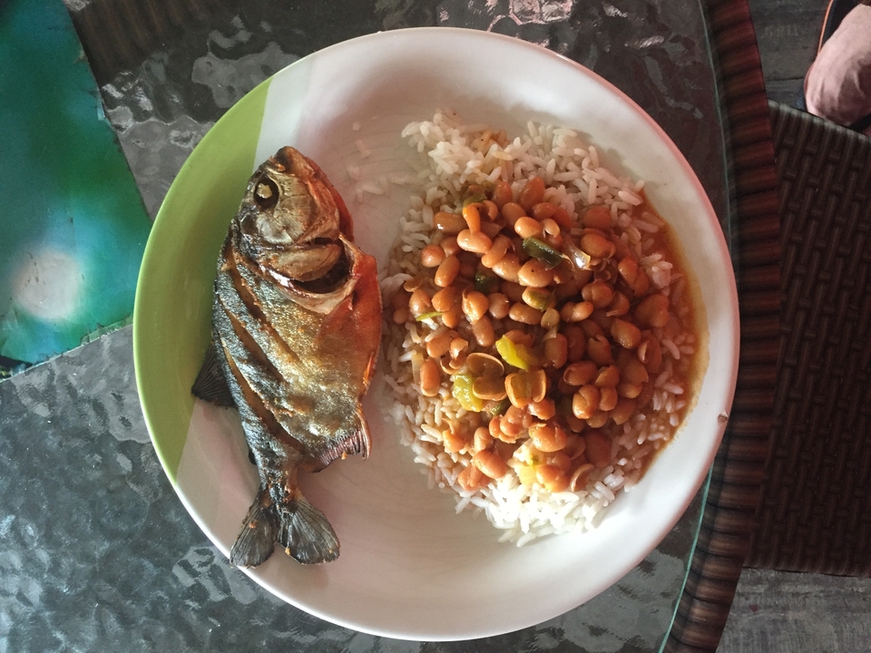 Repas traditionnel avec poisson et haricots servi dans une assiette.