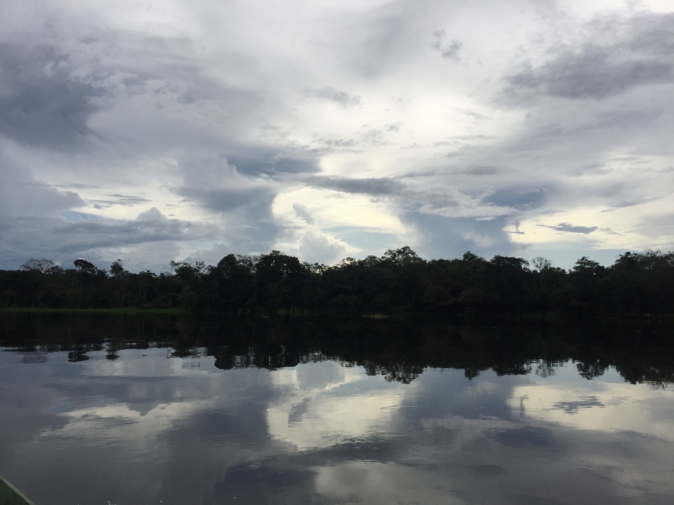 Scène de rivière avec un ciel nuageux se reflétant sur l'eau.