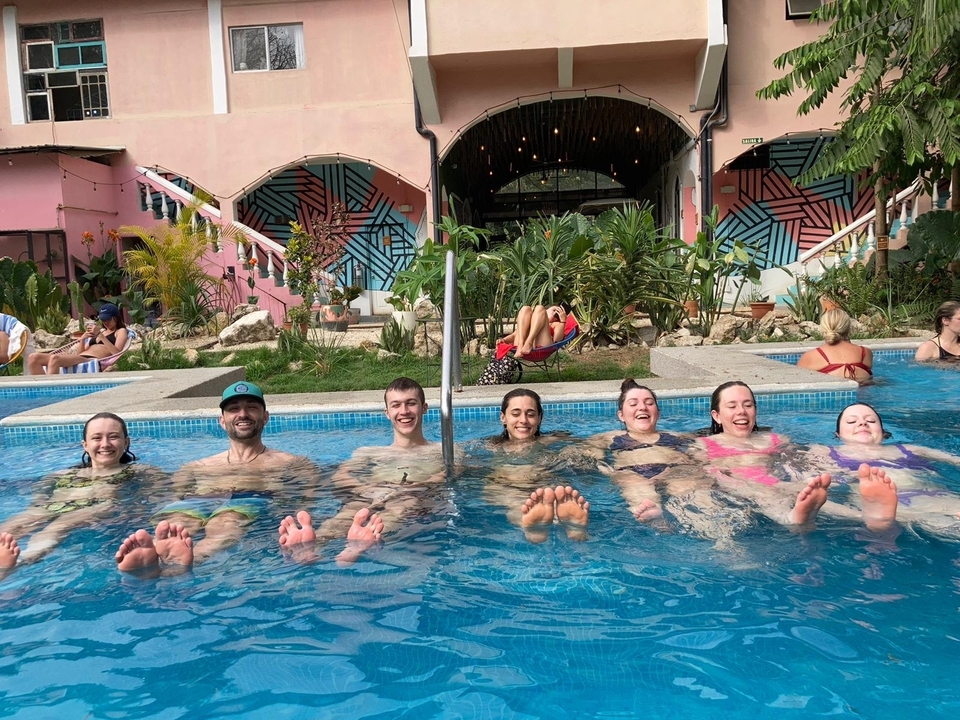 Groupe de personnes profitant d'une baignade dans une piscine avec une fresque murale en arrière-plan.