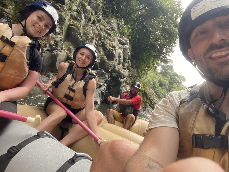 People rafting in a river canyon with life jackets and helmets.
