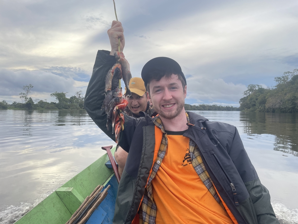 Deux personnes dans un bateau tenant des poissons au-dessus d'une rivière.