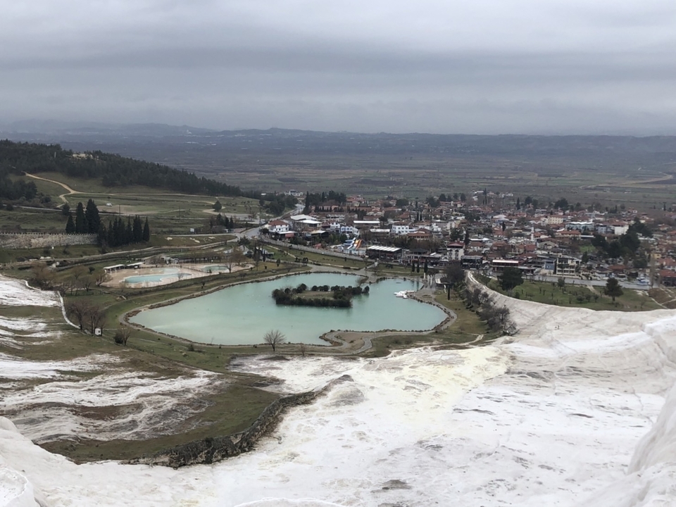 Vue aérienne d'une ville avec une piscine dans un paysage vallonné.