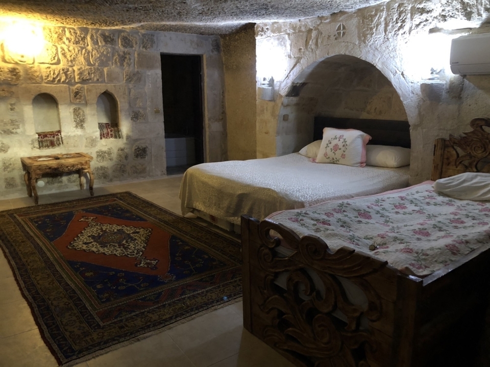 Chambre d'hôtel troglodyte confortable avec tapis décoratifs.