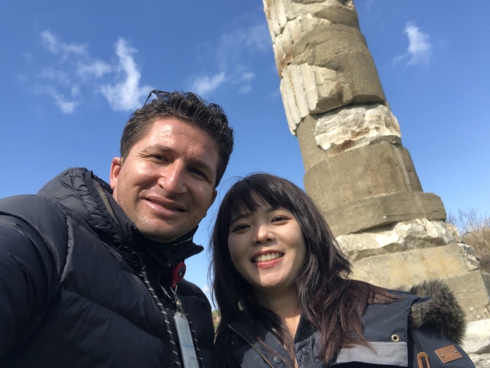 Deux personnes prenant un selfie avec une colonne historique en arrière-plan.
