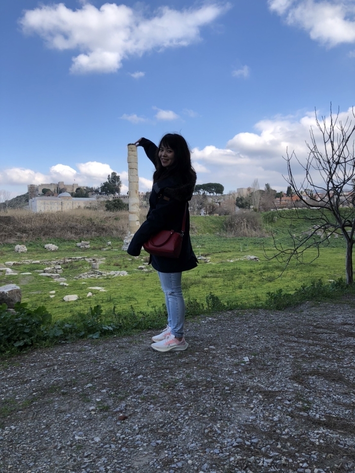 Personne posant avec une colonne sur un site historique.