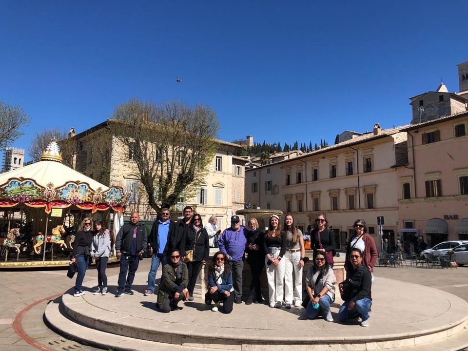 Un groupe de personnes posant sur une place ensoleillée avec un manège.