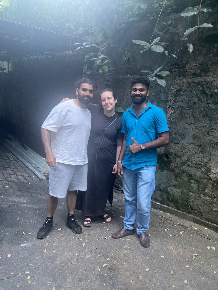 Trois personnes posant ensemble devant un mur de pierre texturé.